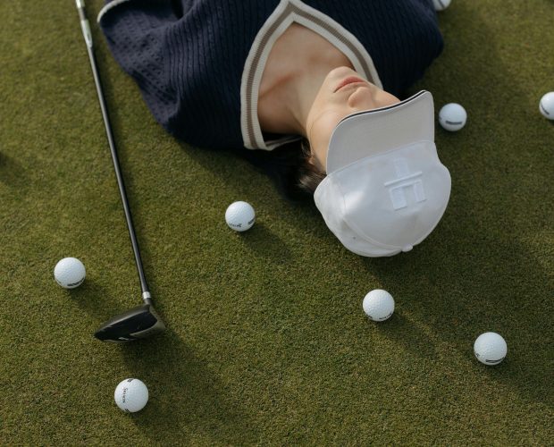 Relaxed women's golfer taking a break on the field with equipment around.